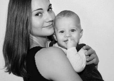 Stolze Mama mit strahlendem Baby auf dem Arm